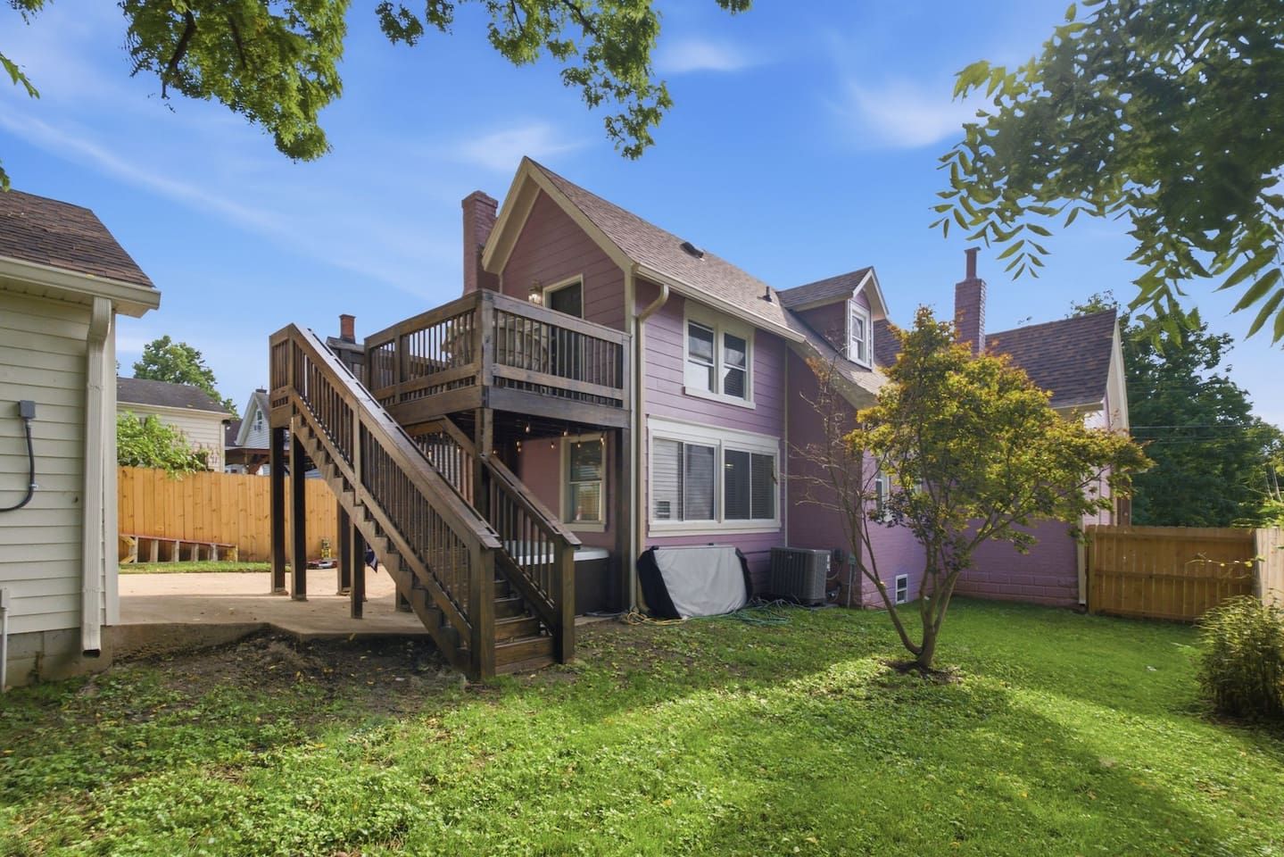 A two-story house with a wooden deck and a staircase leading to the upper floor.