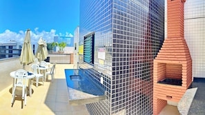Eine Dachterrasse mit Sitzgelegenheiten im Freien, einem kleinen Pool und einem Backofen aus Ziegeln.