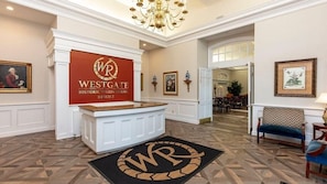 A reception area with a sign for Westgate Historic Williamsburg Resort, a chandelier, framed artwork, and a patterned carpet. - Historic Escape – 1BR Villa at Westgate Williamsburg (Williamsburg)