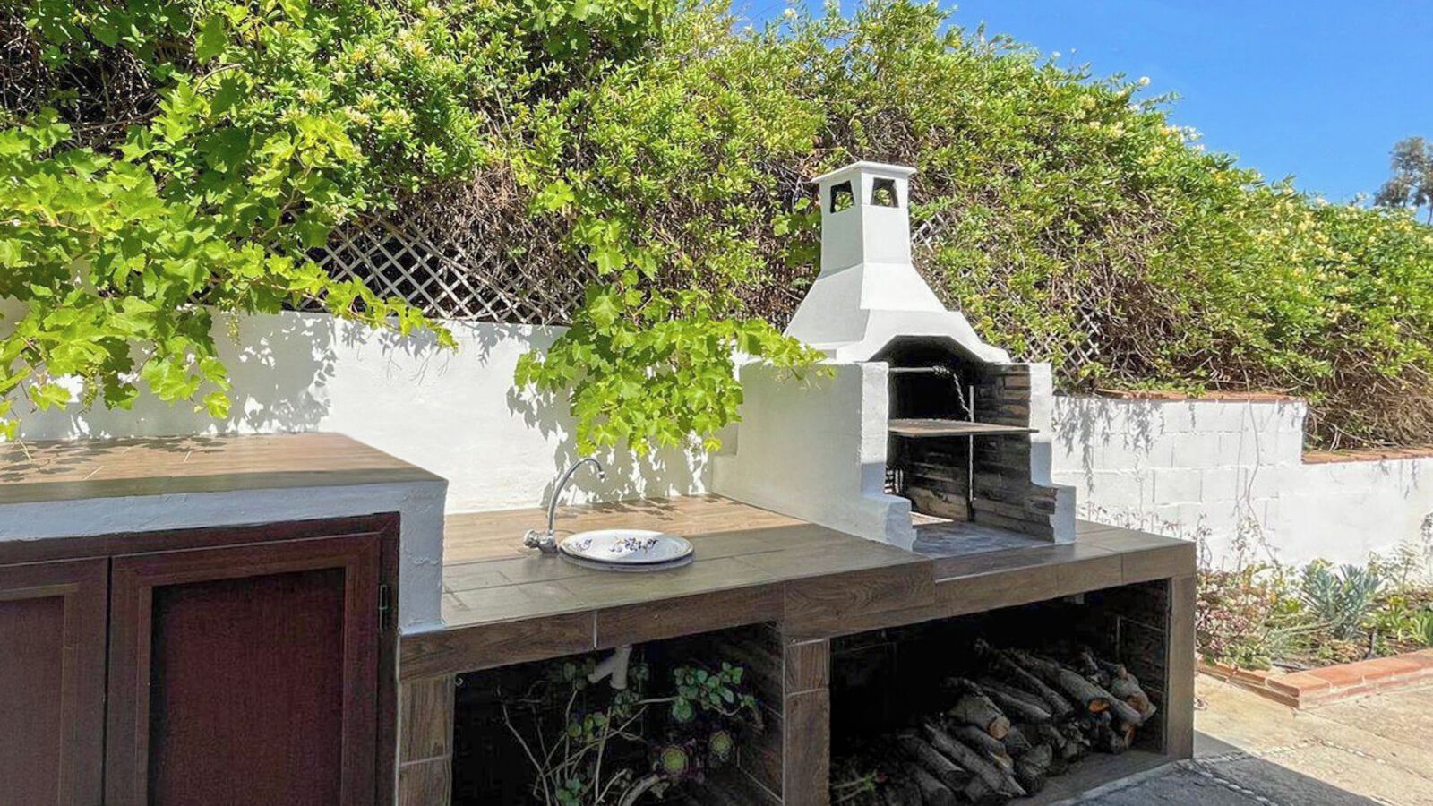 An outdoor kitchen with a built-in grill and a sink.