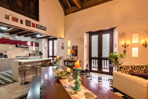 A modern kitchen with bar stools, a dining table with candles, and a sofa in a cozy living area. - La Muralla Rooftop Duplex Jacuzzi & View (Cartagena de Indias)