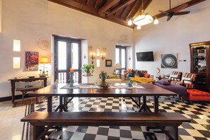 A spacious living room with a checkered floor, a wooden dining table, and a ceiling fan. - La Muralla Rooftop Duplex Jacuzzi & View (Cartagena de Indias)