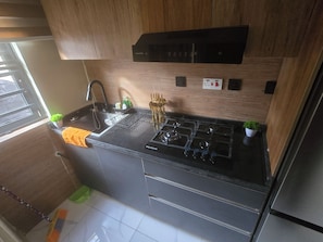 Una cocina moderna con estufa a gas, encimera negra, armarios de madera y una ventana.