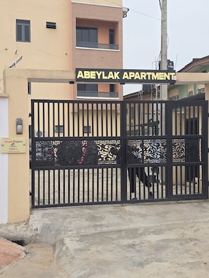 Una entrada con portón a Abeylak Apartments, con un cartel sobre el portón.