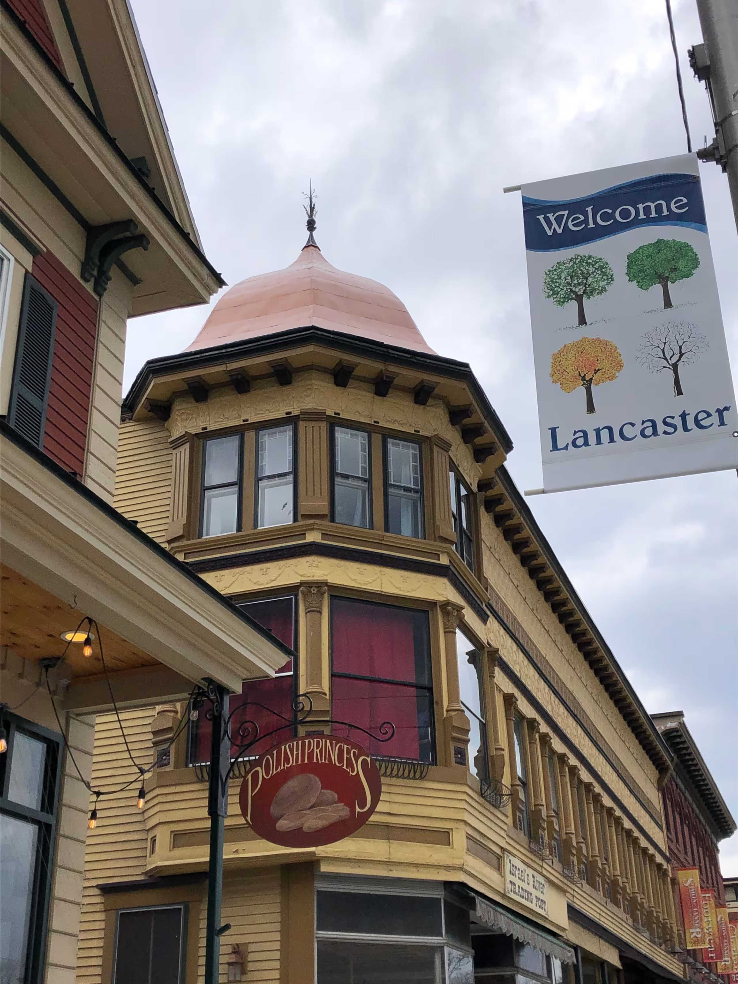 A corner building with a distinctive red dome and a sign reading 'Welcome Lancaster.'