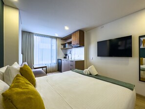 A hotel room with a bed, a desk, a television, and a window with curtains. - Elegant Loft in Usaquen (Bogotá)