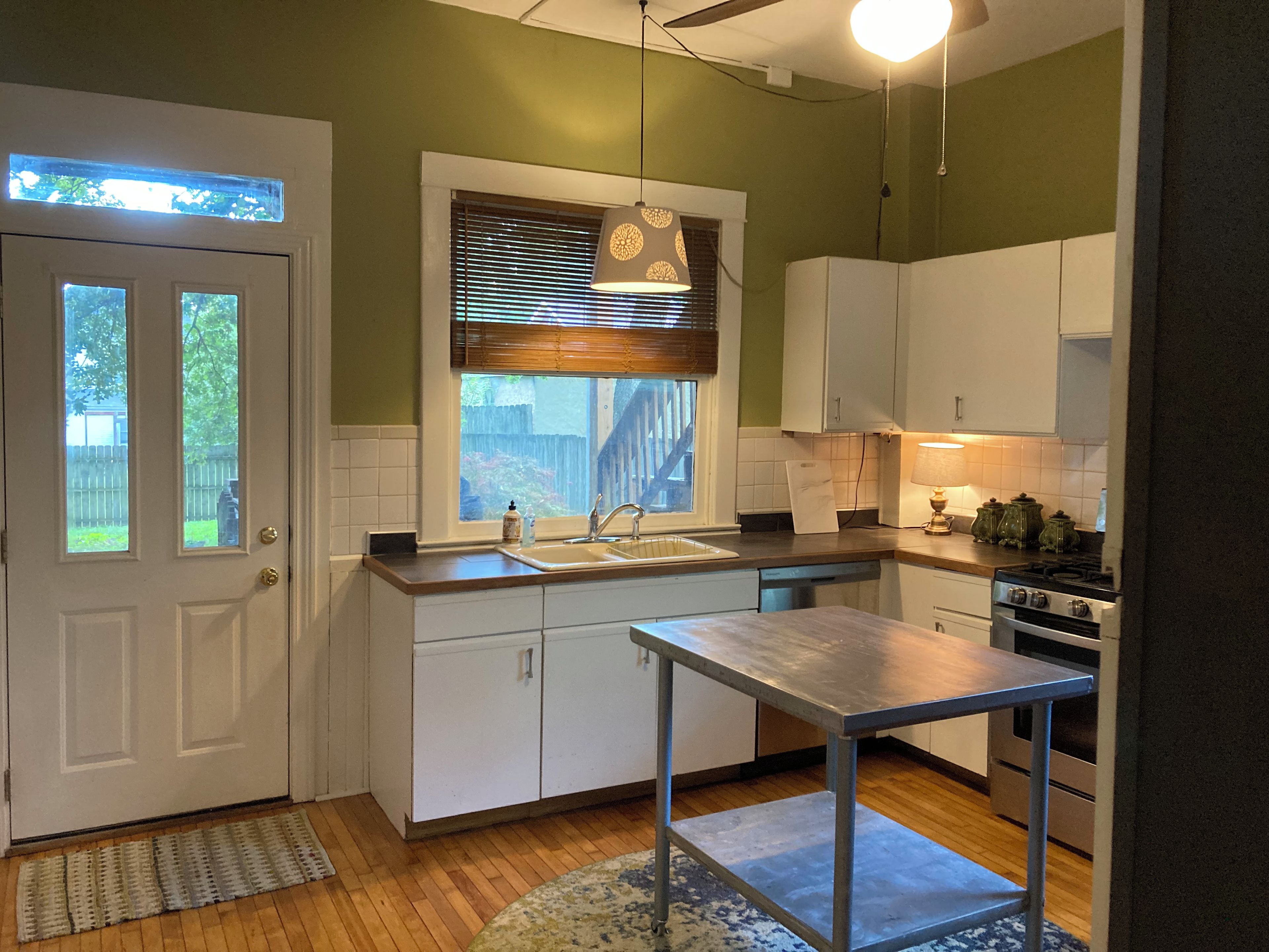 A compact kitchen with white cabinets, a stainless steel sink, and a wooden countertop.