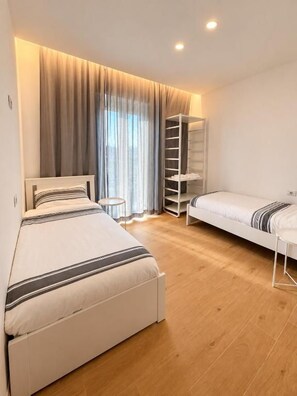 A bedroom with a bed, a bedside table, a wardrobe, and a window with curtains.