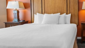 A hotel room with a large bed, a wooden headboard, a nightstand with a lamp, and a small table. - WorldMark Rocky Mountain Preserve - 2BR Twin Suite with Fireplace at 8,000 Ft (Granby)