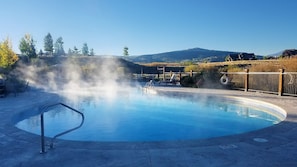 A hot spring pool with a wooden deck, lounge chairs, and a view of hills in the background. - WorldMark Rocky Mountain Preserve - 2BR Twin Suite with Fireplace at 8,000 Ft (Granby)