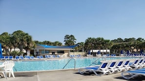 Un área de piscina con sillones reclinables y un edificio al fondo.