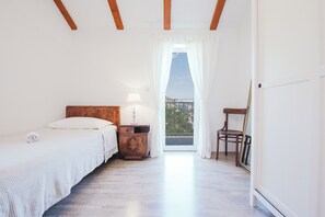 A bedroom with a bed, nightstand, lamp, chair, and a view through a window. - Charming stonehouse Ramiro (Podašpilje)