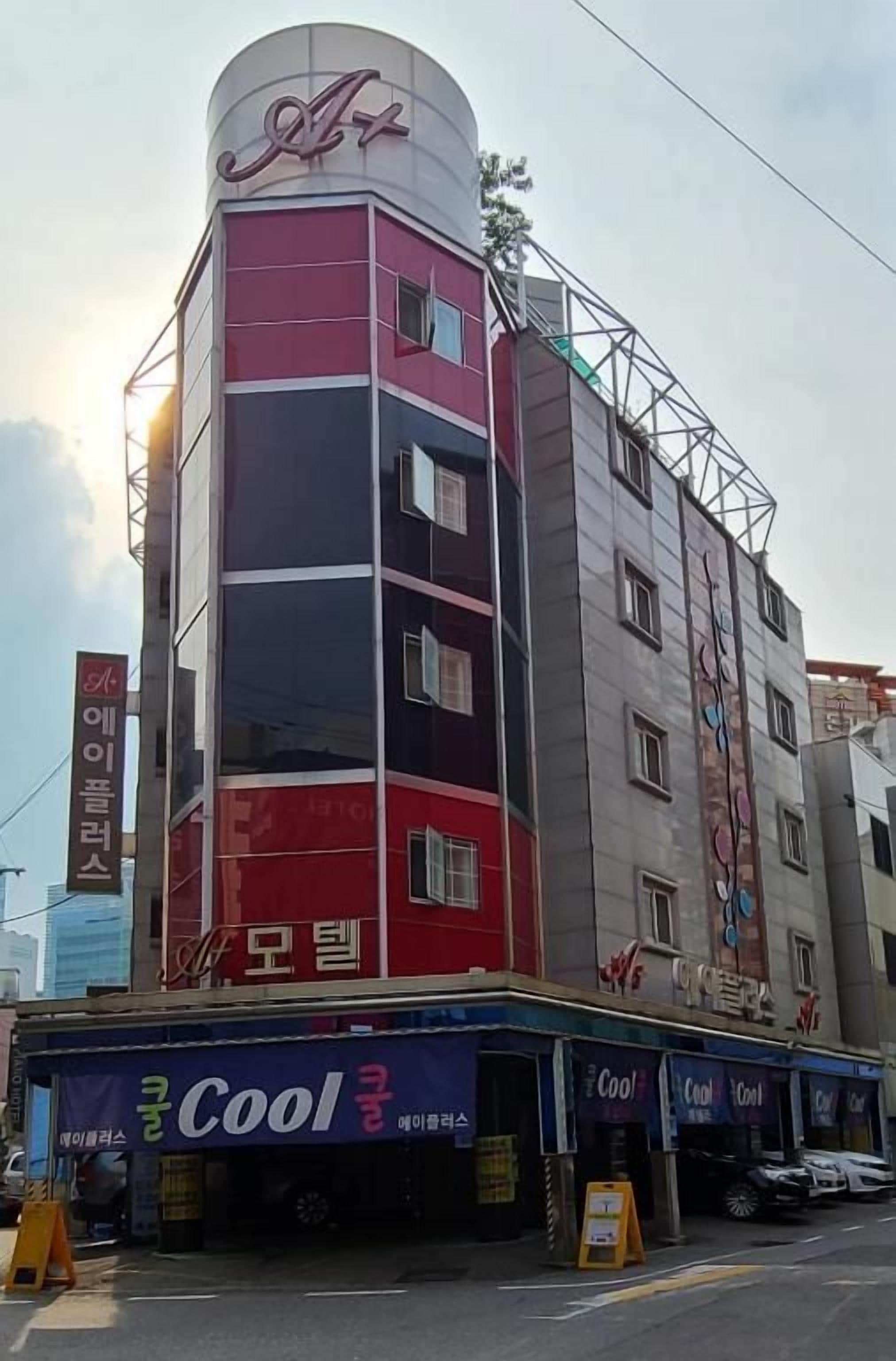 A multi-story building with a prominent red and white facade, a sign with Korean characters, and a storefront with a 'Cool' sign.