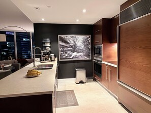Eine moderne Küche mit einer zentralen Kochinsel, Edelstahlgeräten und einem großen Schwarz-Weiß-Foto an der Wand.