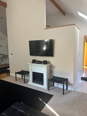 A living room with a fireplace, a flat-screen TV mounted above it, and a black leather sofa. - Cozy 1-bedroom apartment in beautiful Bowie with AC (Bowie)