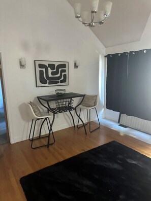 A dining area with a table and chairs, a black rug, and a wall-mounted abstract artwork. - Cozy 1-bedroom apartment in beautiful Bowie with AC (Bowie)