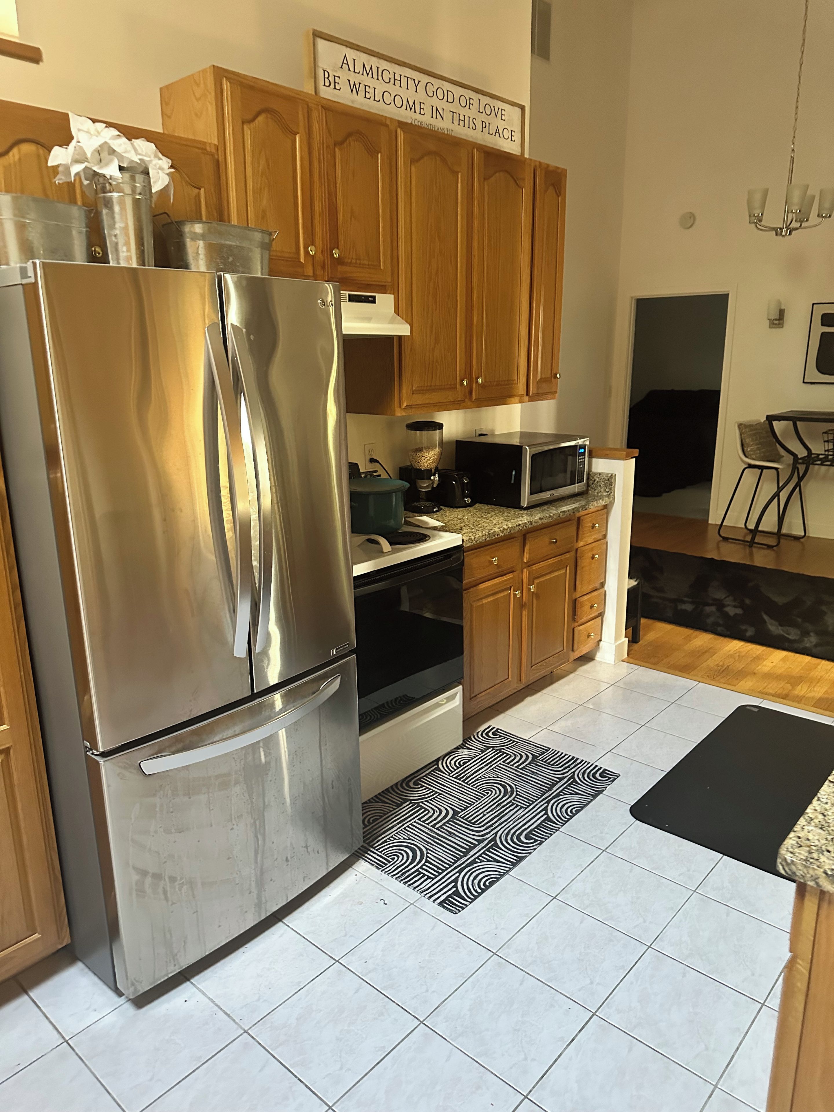A kitchen with stainless steel appliances, wooden cabinets, and a sign above the cabinets.