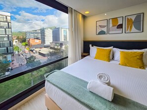 A hotel room with a large bed, a view of the cityscape, and a modern design. - Amazing Loft in Usaquen (Bogotá)