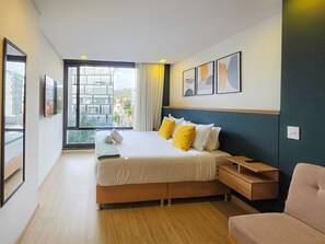 A modern hotel room with a large bed, bedside tables, a view of the city, and artwork on the wall. - Amazing Loft in Usaquen (Bogotá)