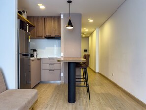 A modern kitchen with a dining area, wooden cabinets, a black hanging light fixture, and a wooden floor. - Amazing Loft in Usaquen (Bogotá)