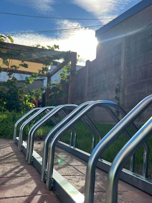 En række cykelstativer op ad en væg med klar himmel i baggrunden.