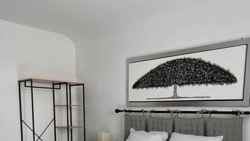 A bedroom with a bed, a headboard, a nightstand, a lamp, a framed picture, and a wardrobe.