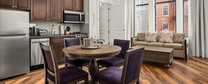Una cocina moderna con refrigerador, estufa, microondas y comedor con sillas y una mesa.
