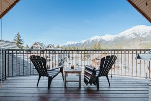 Un balcó amb dues cadires Adirondack, una taula petita i vista a muntanyes nevades.