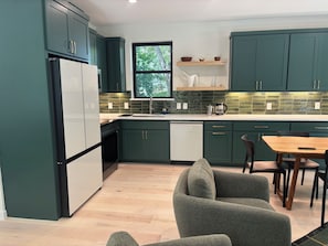 Eine moderne Küche mit grünen Schränken, einem weißen Kühlschrank und einem Holzespeisesaal mit Stühlen.
