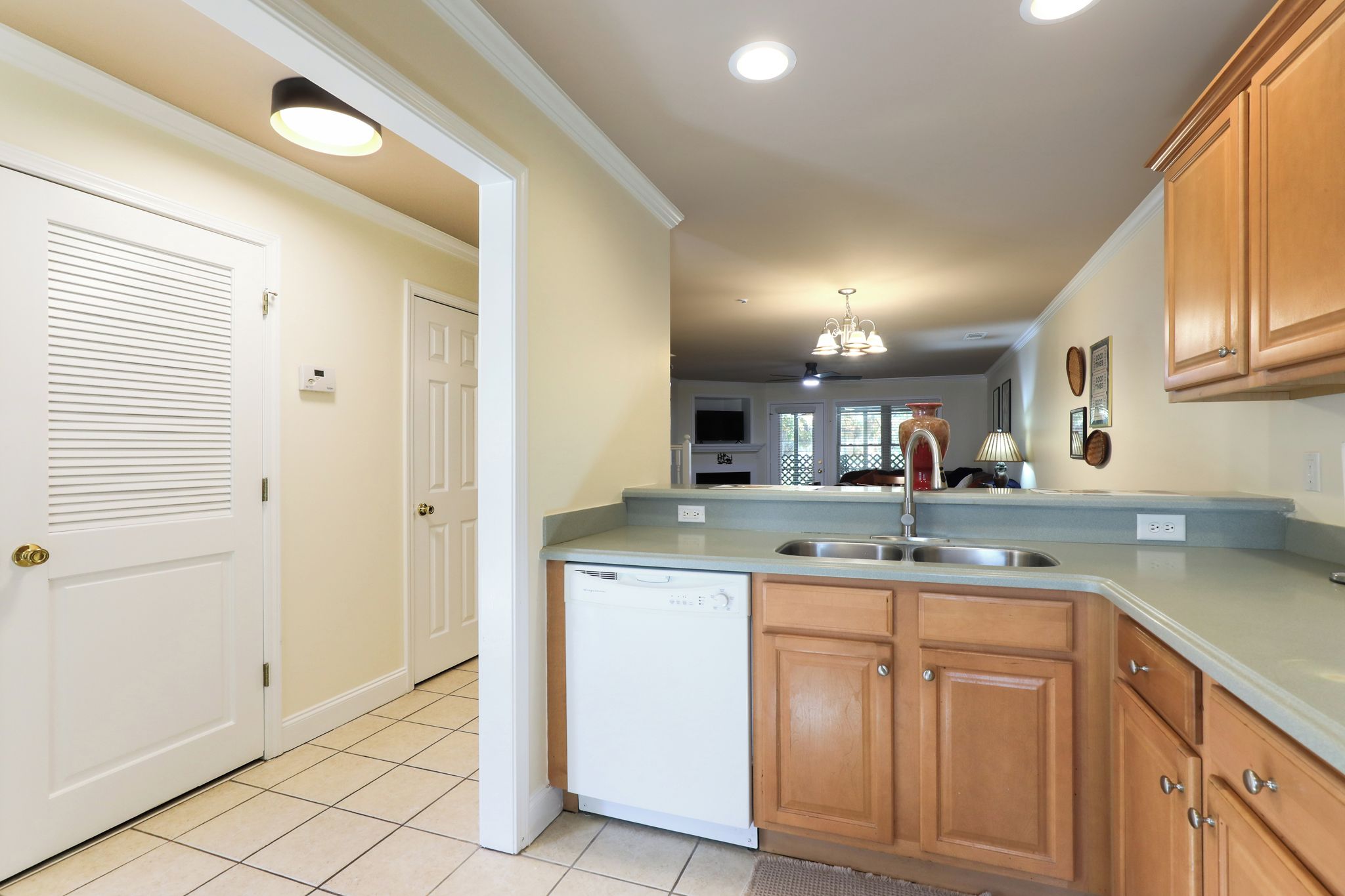 A kitchen with a dishwasher, wooden cabinets, a sink, and a ceiling light fixture.