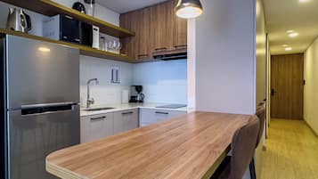 Una cocina moderna con encimera de madera, electrodomésticos de acero inoxidable y una lámpara colgante.