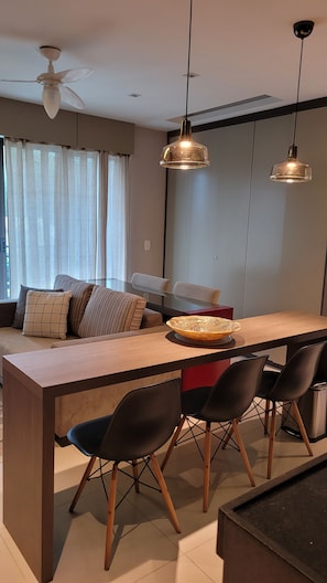 Een moderne keuken met een centraal eiland, zwarte stoelen, hanglampen en een plafondventilator.