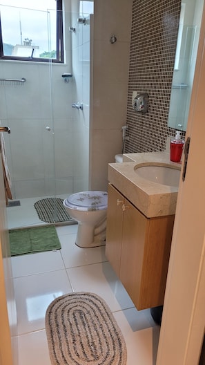 A bathroom with a toilet, sink, and shower area. - New Listing (Petrópolis)