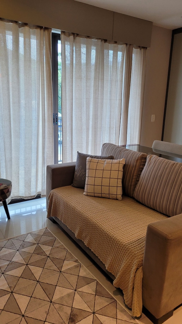 A living room with a sofa, a patterned rug, and sheer curtains. - New Listing (Petrópolis)