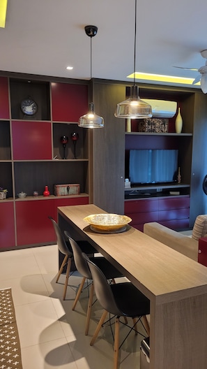 A modern kitchen with a wooden island, pendant lights, and a built-in TV. - New Listing (Petrópolis)