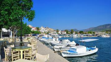 A marina with boats docked, a row of outdoor seating, and buildings in the background.