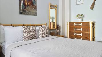 Un dormitorio con una cama grande, un aparador de madera, un espejo y un cuadro en la pared.