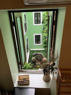 Ein Fenster mit Blick auf ein grünes Gebäude und eine mit 'WOOD BOX' beschriftete Holzkiste auf einer weißen Ablagefläche.