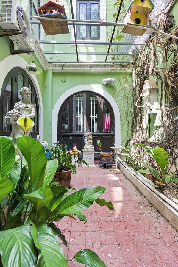 A courtyard with a statue, potted plants, and a birdhouse. - The Bambu Room at Casa of Essence | Old San Juan Comfort (San Juan)