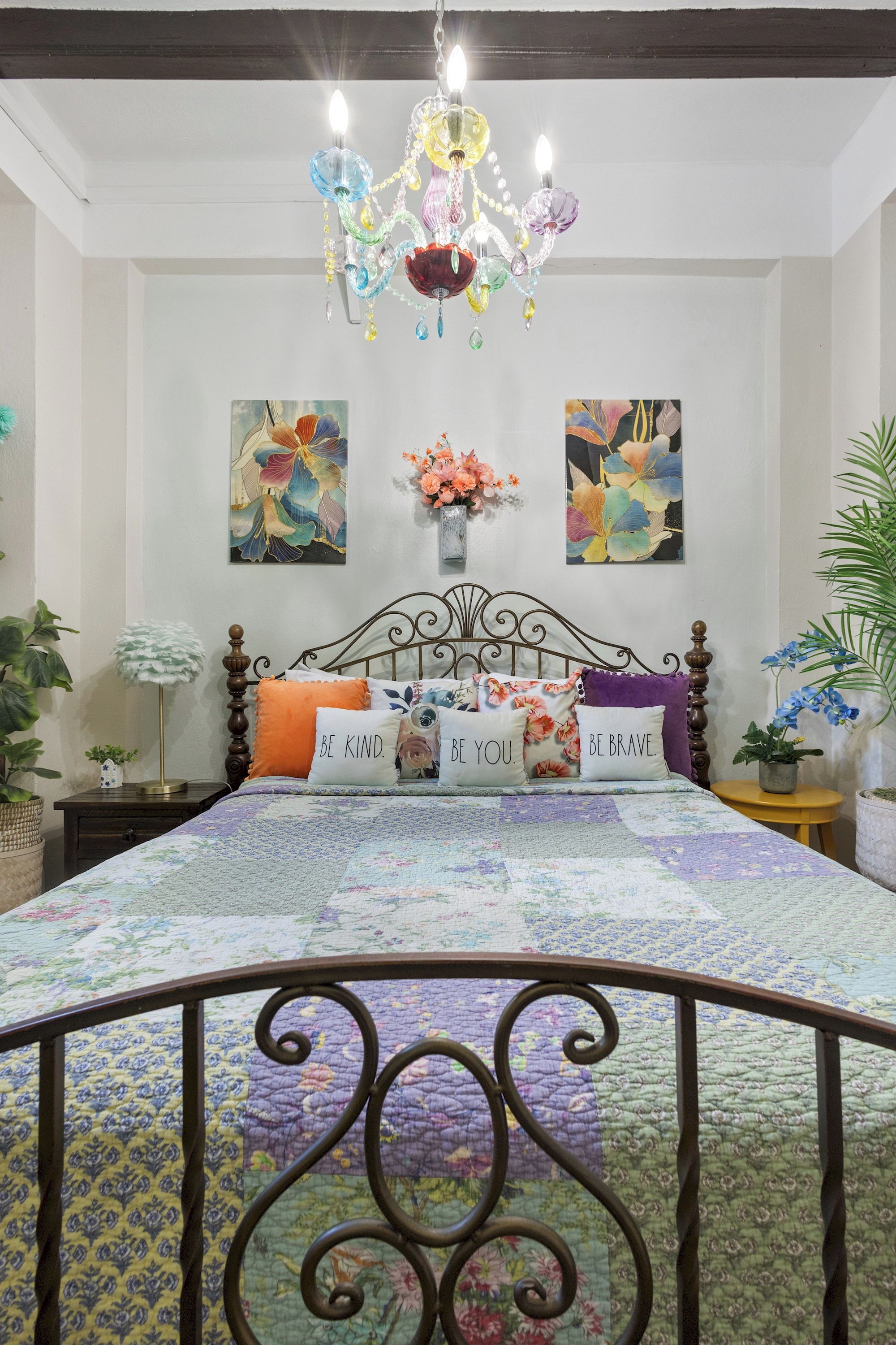 Un dormitorio con cama, candelabro, decoración en la pared y plantas en macetas.