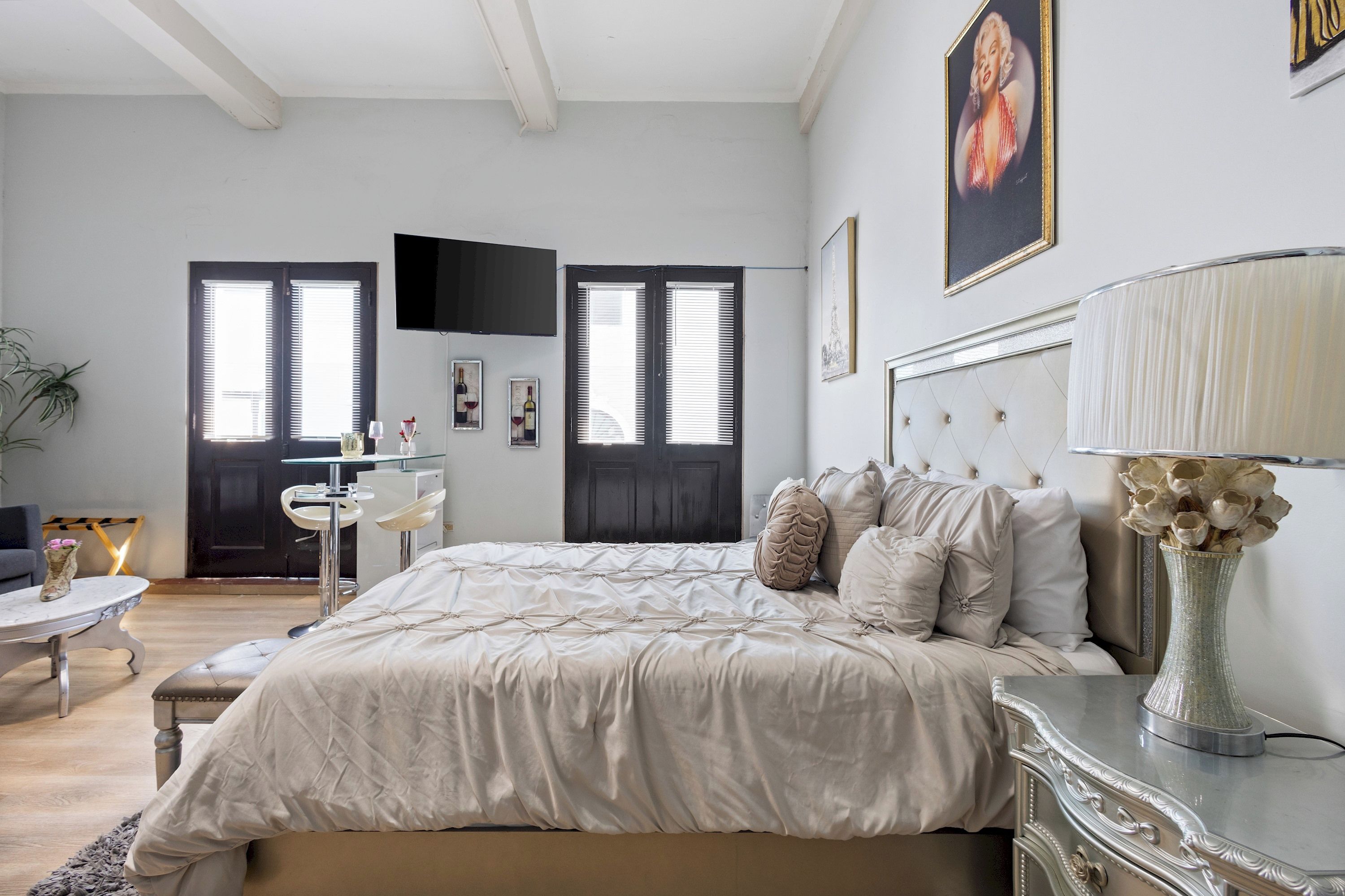 Une chambre à coucher avec un grand lit, un bureau, une chaise, une télévision et un tableau accroché au mur.