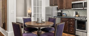 Een moderne keuken met een ronde eettafel, paarse stoelen, een koelkast, een magnetron en een oven.