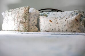A bed with two pillows, one with a floral pattern and the other with birds. - The PR Suite at Casa of Essence | Old San Juan Encanto (San Juan)
