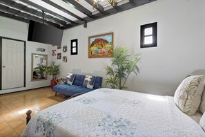 Une chambre à coucher avec un lit, un canapé, un tableau et une plante en pot.