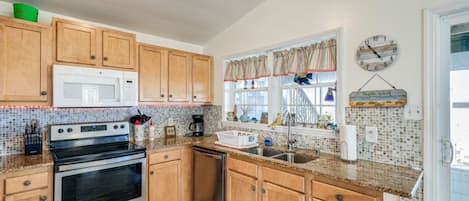 A kitchen with wooden cabinets, a microwave, stove, and a sink.