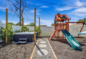 A backyard with a wooden play structure, a slide, a hot tub, and a path marked with circles. - Bradenton Escape w/ Fire Pit, Pool & Putting Green (Bradenton)