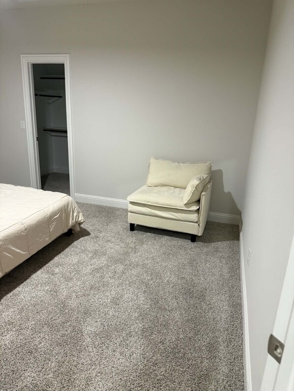 Een slaapkamer met een bed, een stoel en een kast.