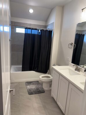 Een badkamer met een bad, toilet en douchegordijn.