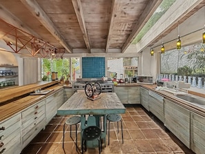 A spacious kitchen with a large island, wooden cabinets, and a view of greenery outside. - Villa Oasis del Cielo · Vista al Lago y Montaña (Valle de Bravo)