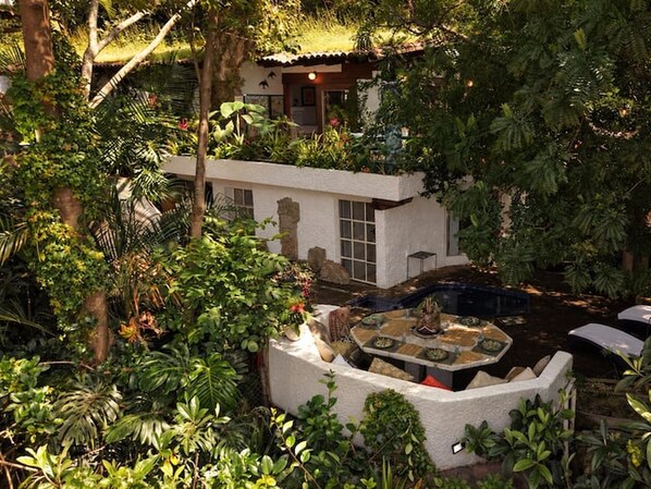 Un jardin avec une piscine, un espace patio et un bâtiment à l’extérieur blanc et doté de grandes fenêtres.